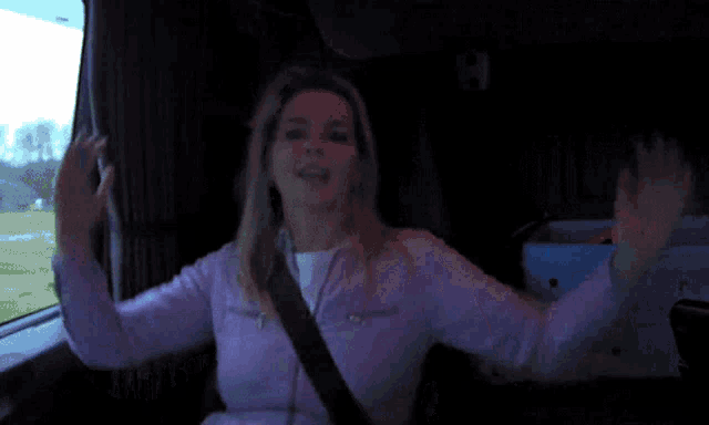 a woman is sitting in a car with her arms outstretched