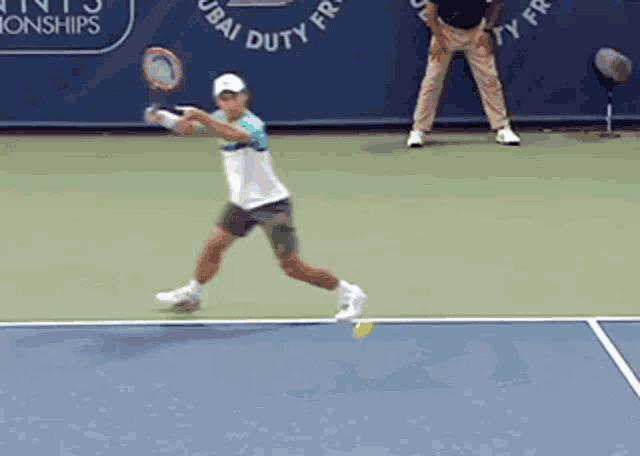 a tennis player is swinging a racket on a court with a sign that says dubai duty free