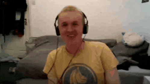a man wearing headphones and a yellow shirt with a banana on it is smiling .