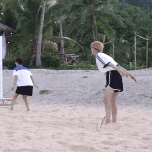 a man and a woman are playing volleyball on the beach