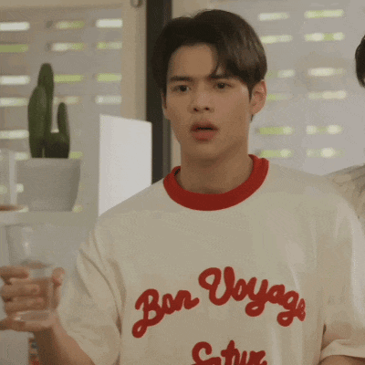 a man wearing a bon voyage shirt is holding a glass