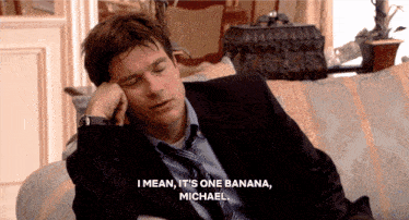 a man in a suit and tie is laying on a couch and saying " i mean it 's one banana "