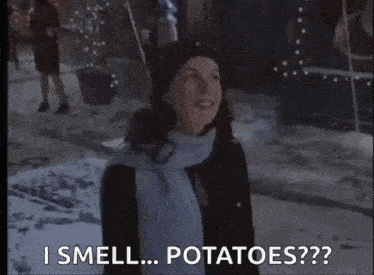 a woman wearing a scarf and hat is standing in the snow and says i smell potatoes
