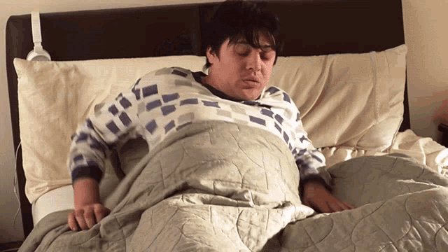a man is laying on a bed with a blanket and pillow