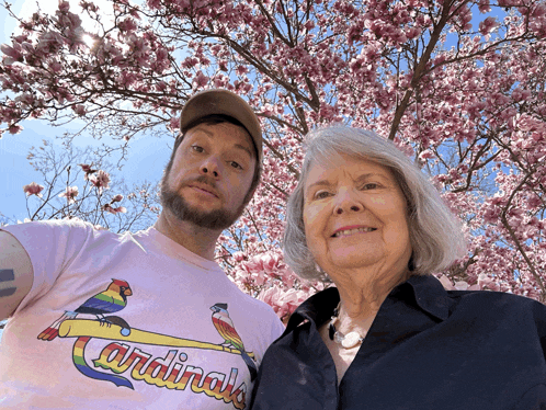 a man wearing a pink cardinals shirt stands next to a woman