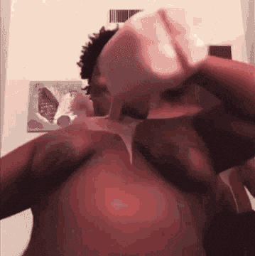 a man without a shirt is drinking from a bottle .