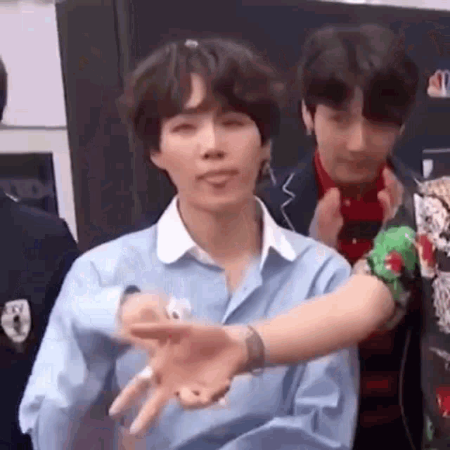 a man in a blue shirt is making a funny face while holding his hand out .