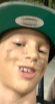 a young boy wearing a green hat with a sticker on it that says " never trust "