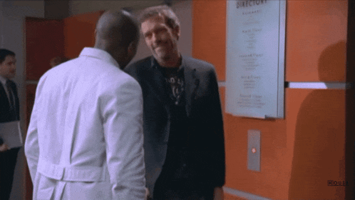 two men shaking hands in front of a directory sign
