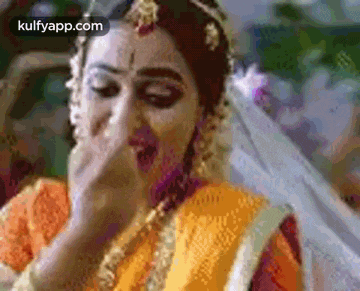 a bride is covering her mouth with her hand while wearing a veil .