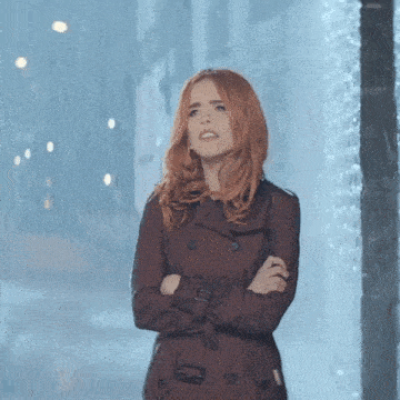 a woman in a trench coat stands in the rain