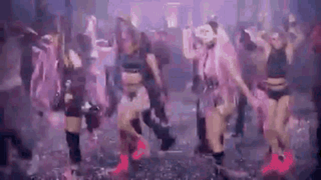 a group of women are dancing in a club in purple lights .