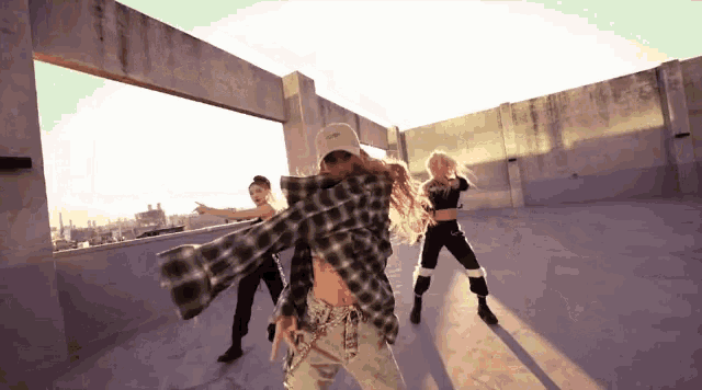a woman in a plaid shirt is dancing on a rooftop with other women