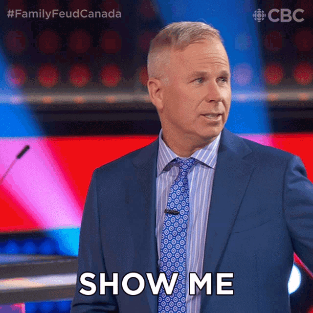 a man in a suit and tie says show me in front of a microphone