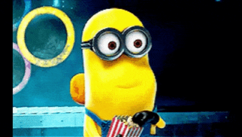 a cartoon minion is holding a bag of popcorn and wearing goggles .
