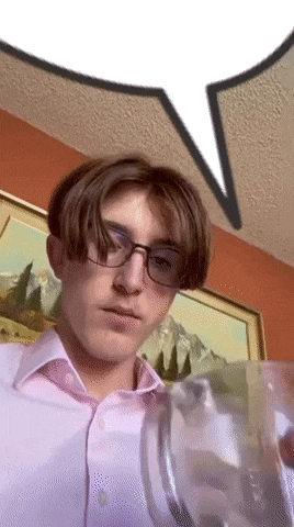 a young man wearing glasses and a pink shirt is holding a glass of water