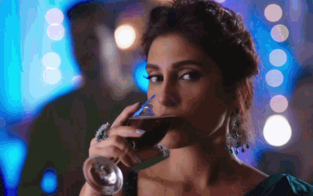 a woman is drinking a glass of wine with a blue background