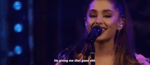 ariana grande is singing into a microphone on a stage and saying `` he giving me that good shit '' .