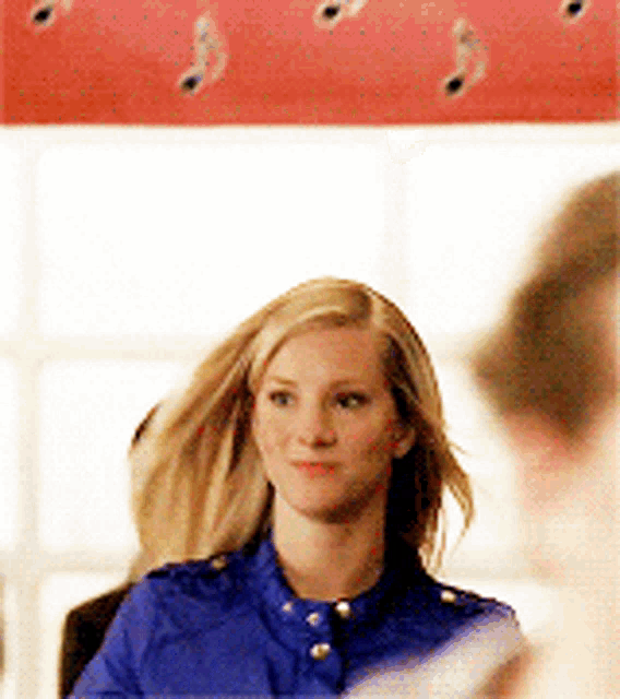 a woman in a blue shirt is sitting in a chair