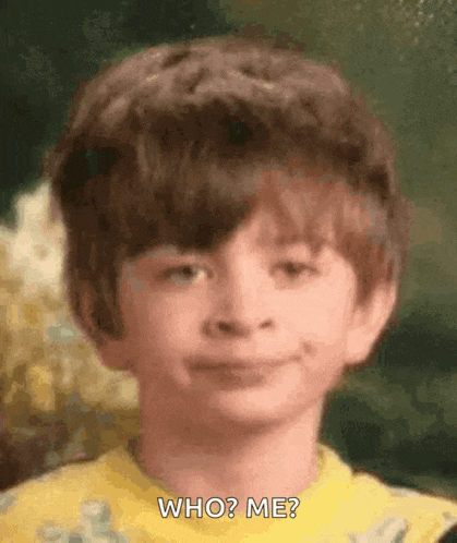 a young boy is making a funny face and asking who ? me ?