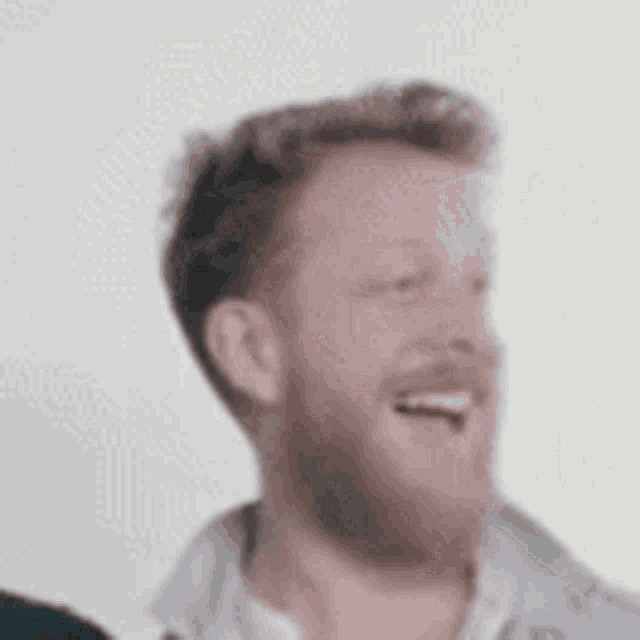 a man with a beard is laughing and clapping his hands .