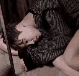 a man in a black and white sweater is laying on the floor