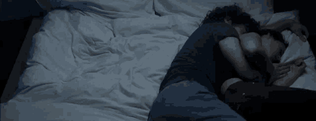 a man and a woman are sleeping on a bed with white sheets