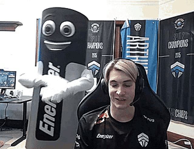 a man wearing headphones is sitting next to a mascot that says energizer