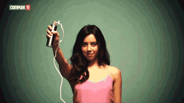 a woman in a pink tank top is holding a spray can in front of a complex tv banner