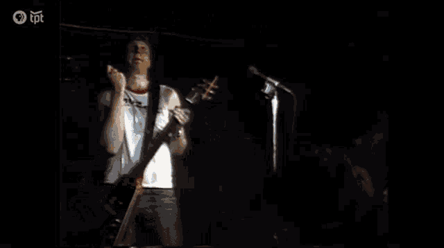 a man in a muza shirt is playing a guitar on stage