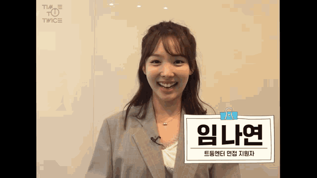 a woman in a suit is smiling with a sign that says i 'm nayeon