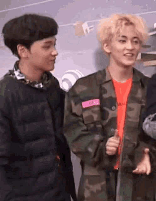 a couple of young men are standing next to each other .