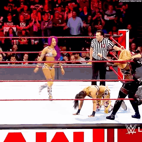 a woman in a bikini is standing on her head in a wrestling ring with a referee