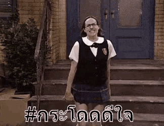 a woman in a school uniform is standing on a set of stairs in front of a door .