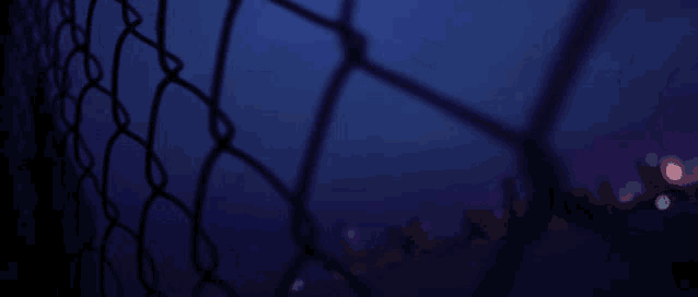 a blurry picture of a chain link fence with a red white and blue glitch effect behind it