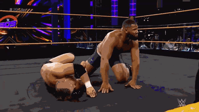two men are wrestling in a wrestling ring with the letters w on the bottom right