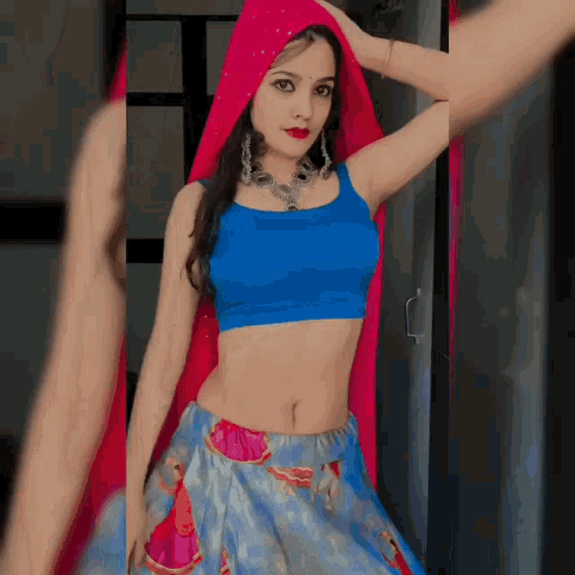 a woman wearing a blue top and a blue skirt with a pink scarf around her head