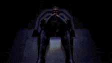 a man in a black suit is sitting in a chair in the dark .