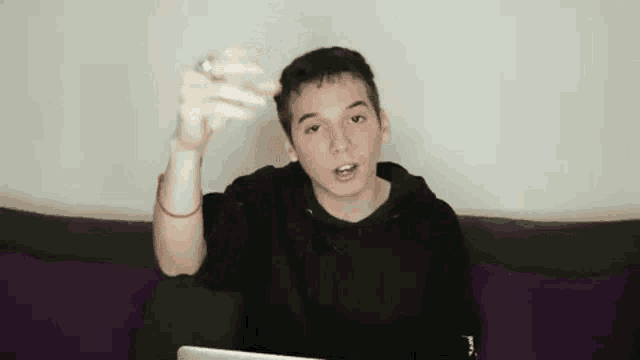 a young man is sitting on a couch holding something in his hand .