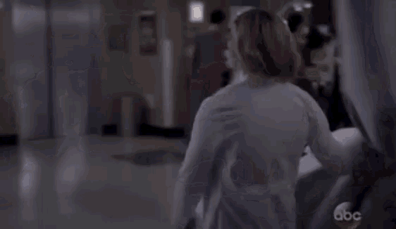 a woman in a lab coat is standing next to a hospital bed in a hospital room .