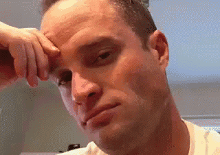 a man wipes his forehead with his hand and looks at the camera