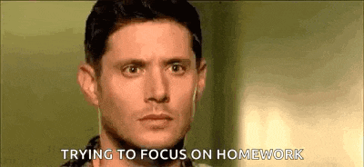 a man is trying to focus on homework while wearing ear buds .