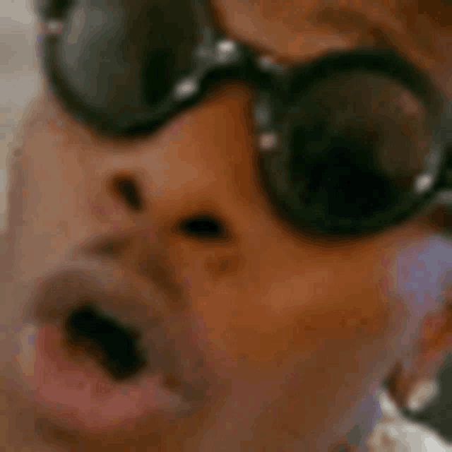 a man wearing a hat and sunglasses is making a funny face .