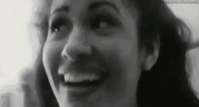 a black and white photo of a woman smiling with her mouth open .