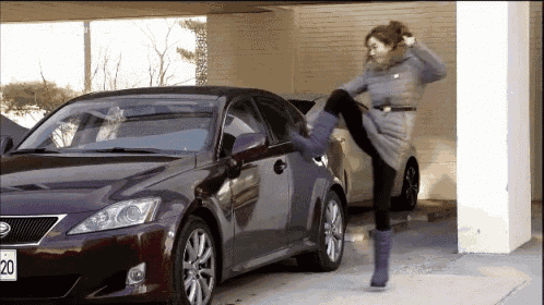 a woman is kicking a purple car with a license plate that says 20