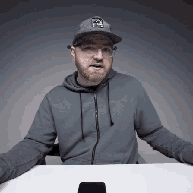 a man wearing a grey hoodie and a hat with a sticker that says ' rvca ' on it