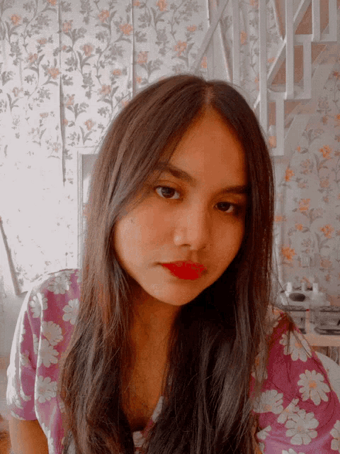 a girl with long hair and red lipstick is wearing a purple shirt with daisies on it