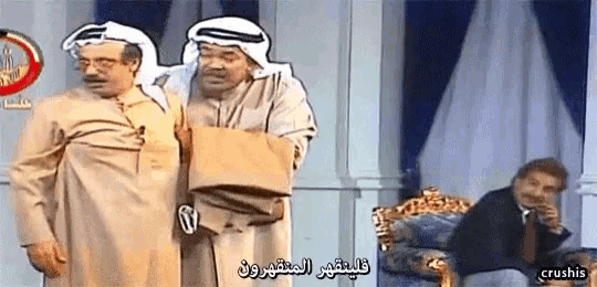 two men are standing next to each other and one is holding a bag with arabic writing on it