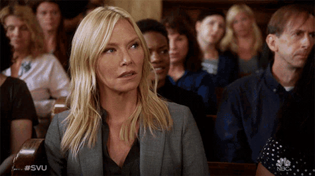 a woman in a suit sits in a courtroom with a #svu sticker on her shirt