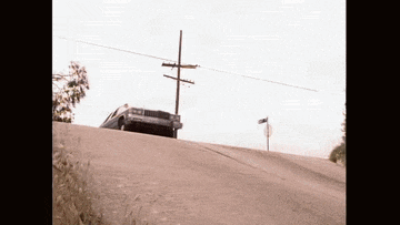 a car is driving down a dirt road with a no left turn sign